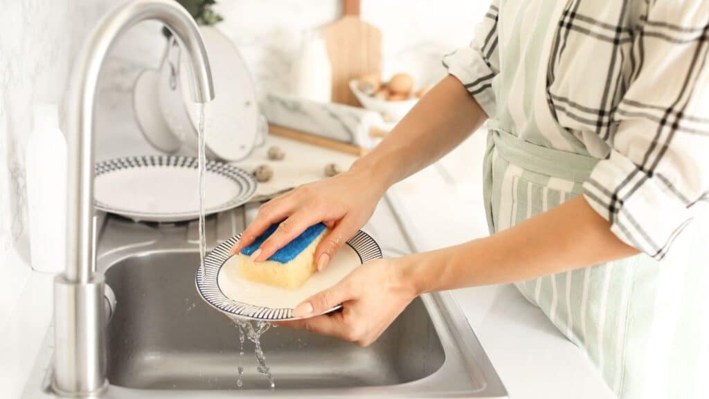 Best nontoxic cleaning products for kitchen, best non toxic dishwashing cleaners and dishwasher powders and tabs. Picture of person washing dishes.